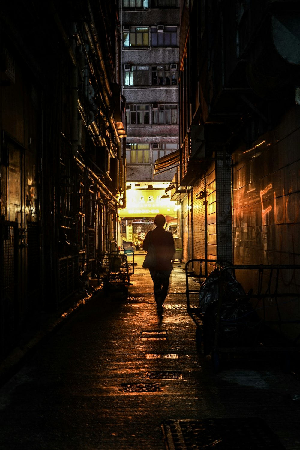 femme en robe noire marchant sur le trottoir pendant la nuit