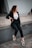 woman in black blazer and black pants sitting on concrete wall during daytime