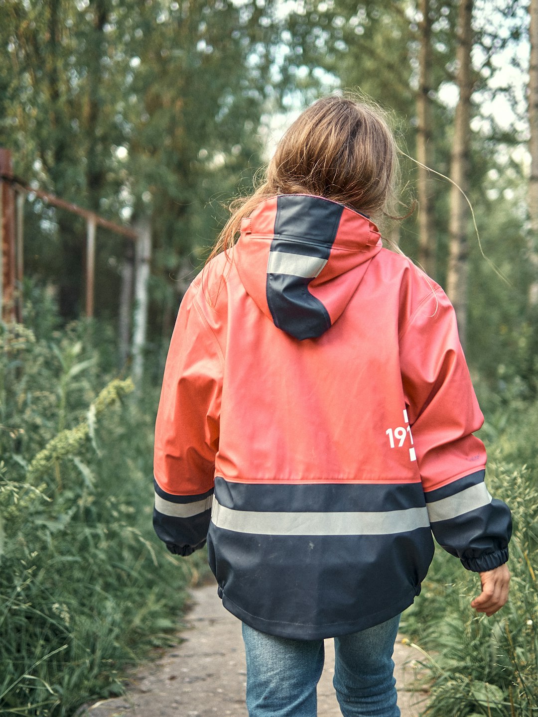 woman in red and black jacket standing near green plants during daytime