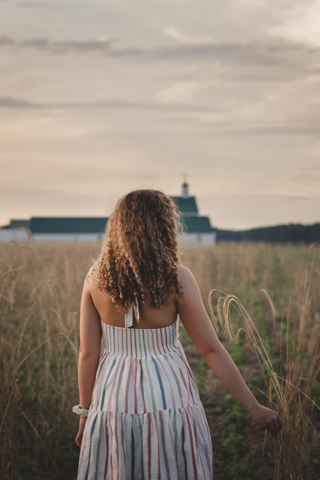 woman in white and black stripe tank dress standing on green grass field during daytime