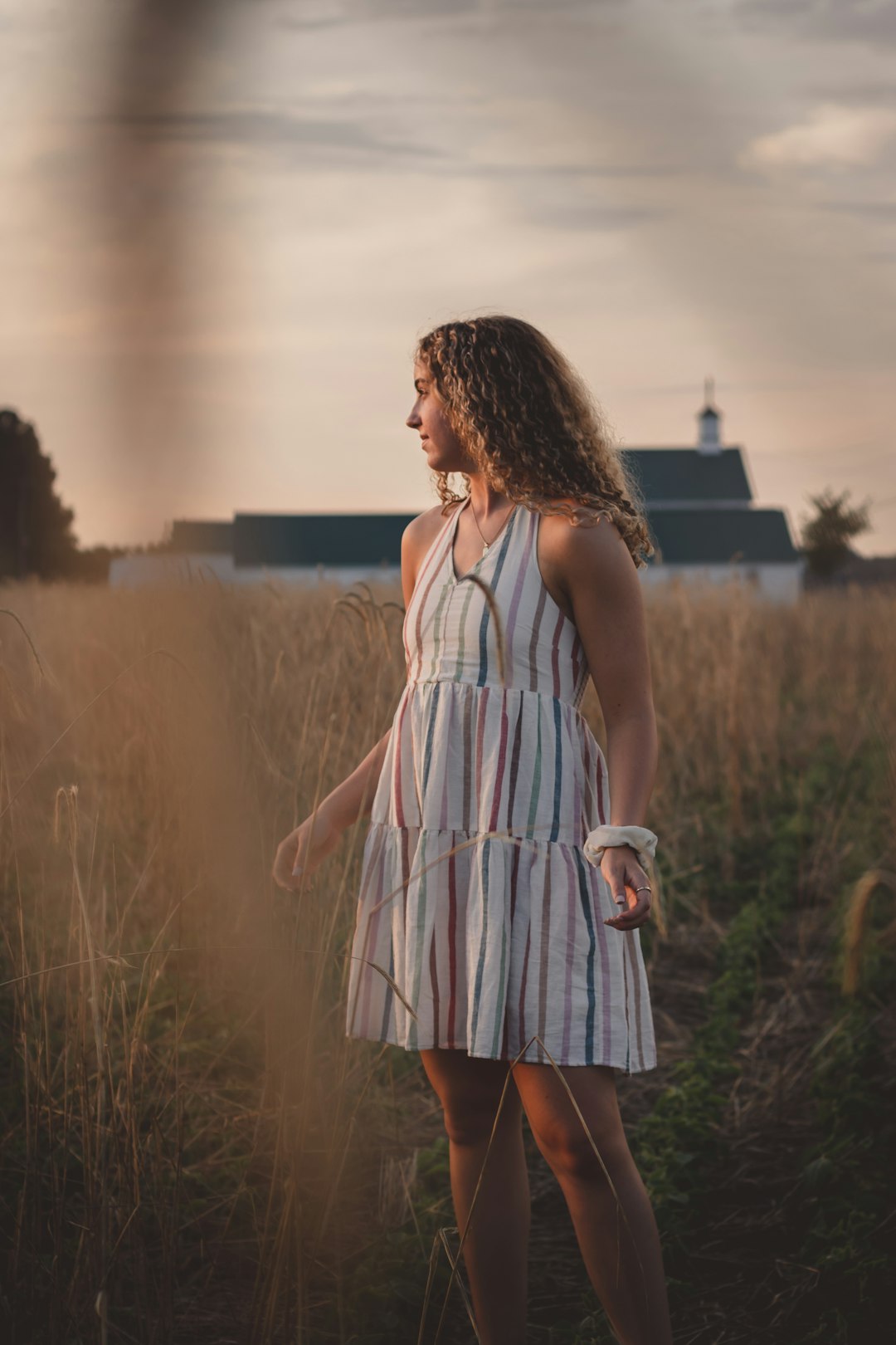 woman in white and pink stripe sleeveless dress standing on green grass field during daytime