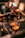 A close-up view of espresso being brewed into two small glass cups from a coffee machine. A hand is holding the portafilter, and the rich, dark liquid is flowing smoothly. The warm lighting enhances the inviting, aromatic ambiance typical of a cozy cafe setting.