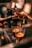 A close-up view of espresso being brewed into two small glass cups from a coffee machine. A hand is holding the portafilter, and the rich, dark liquid is flowing smoothly. The warm lighting enhances the inviting, aromatic ambiance typical of a cozy cafe setting.