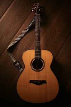 brown acoustic guitar on brown wooden floor