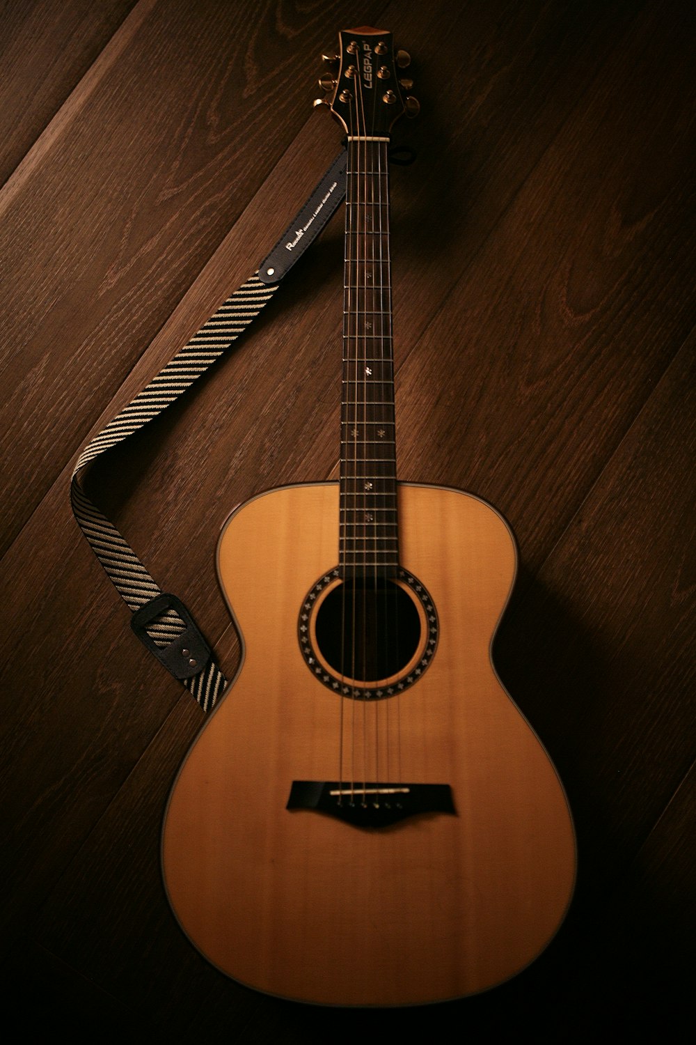 Guitarra acústica marrón sobre suelo de madera marrón