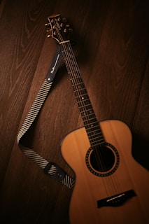 brown acoustic guitar on brown wooden floor