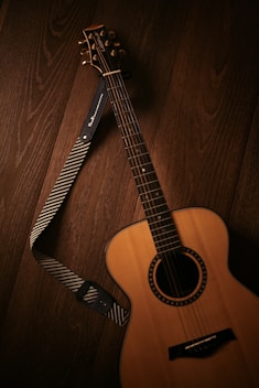 brown acoustic guitar on brown wooden floor
