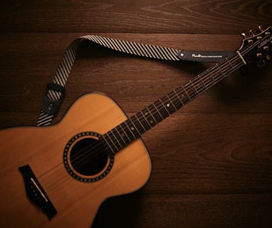 brown acoustic guitar on brown wooden floor