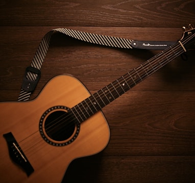 brown acoustic guitar on brown wooden floor