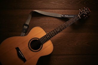 brown acoustic guitar on brown wooden floor