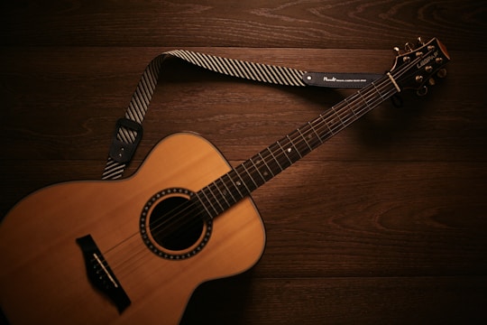 brown acoustic guitar on brown wooden floor