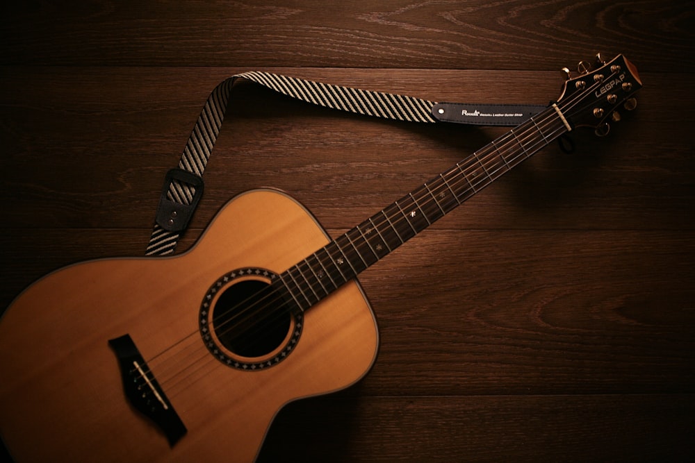 Guitarra acústica marrón sobre suelo de madera marrón