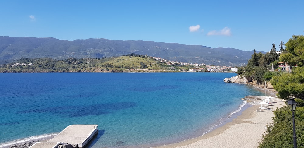 blue sea near green mountain under blue sky during daytime