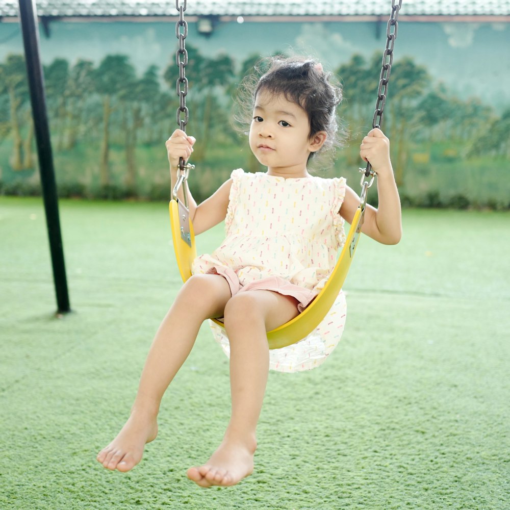 girl in pink dress sitting on swing during daytime