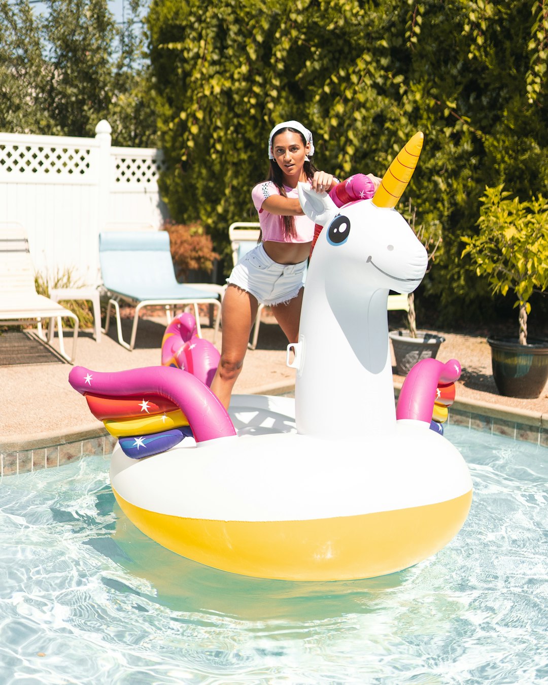 woman in white tank top sitting on white and green inflatable pool float during daytime