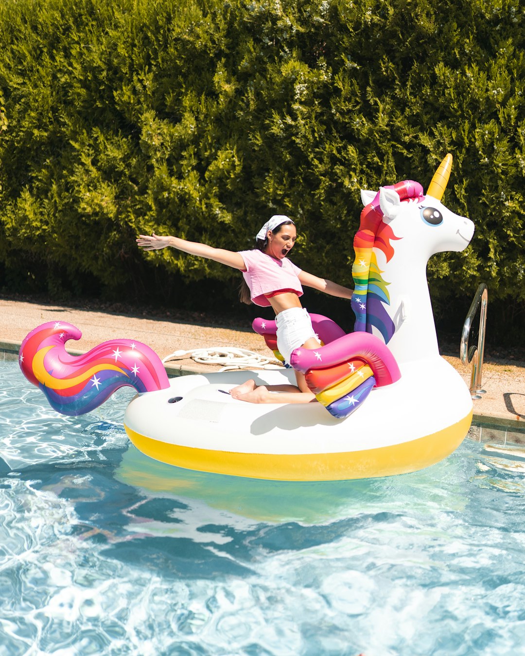 girl in pink shirt riding on inflatable ring on swimming pool during daytime