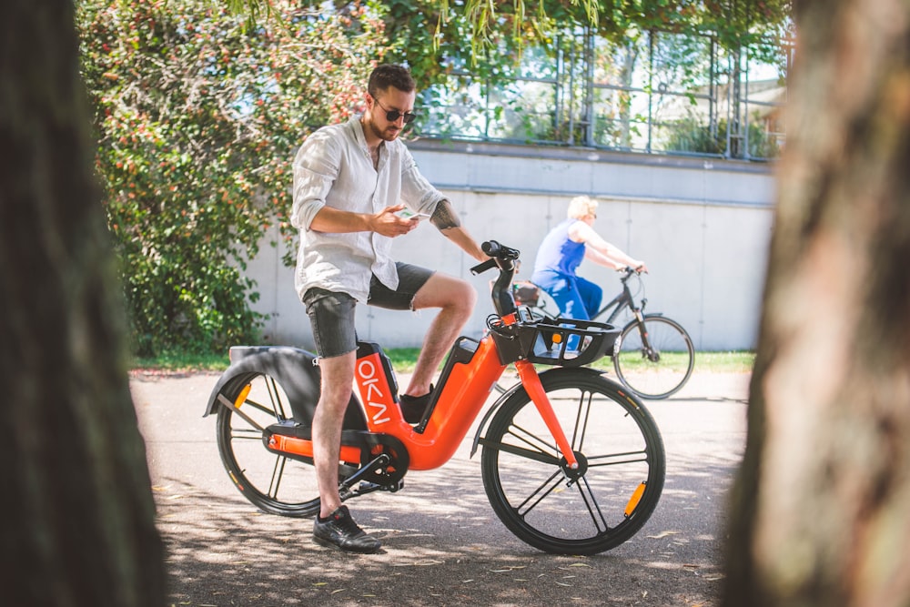 man in white dress shirt riding on orange bicycle during daytime
