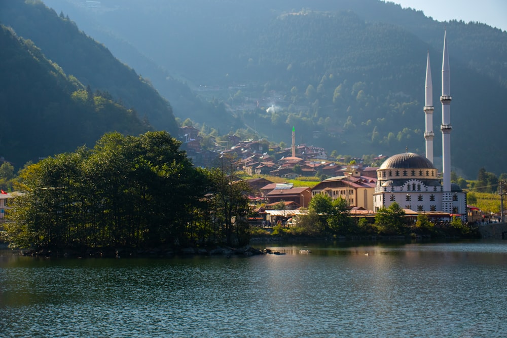 white and brown concrete building near green trees and lake during daytime