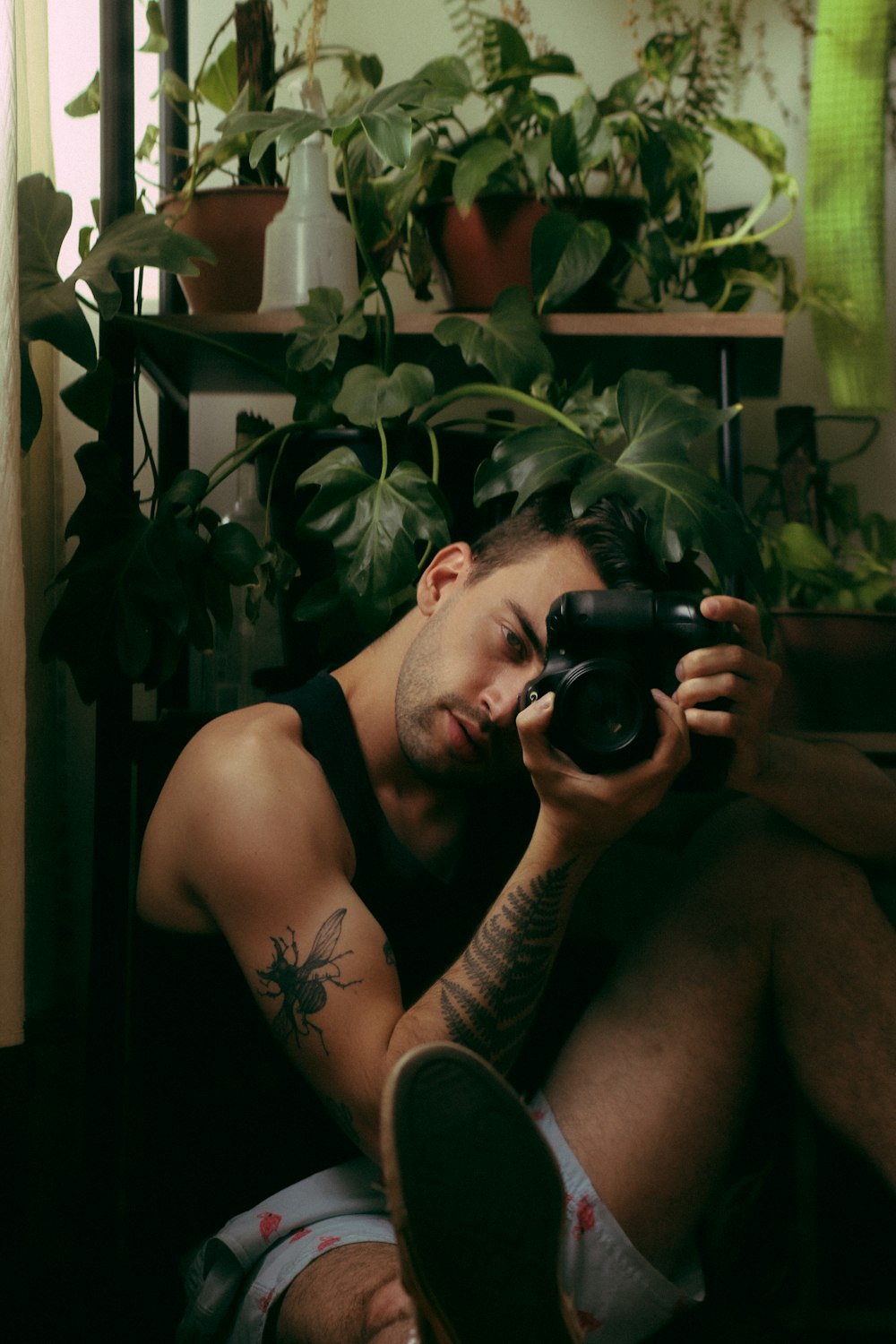 man in black tank top holding black dslr camera