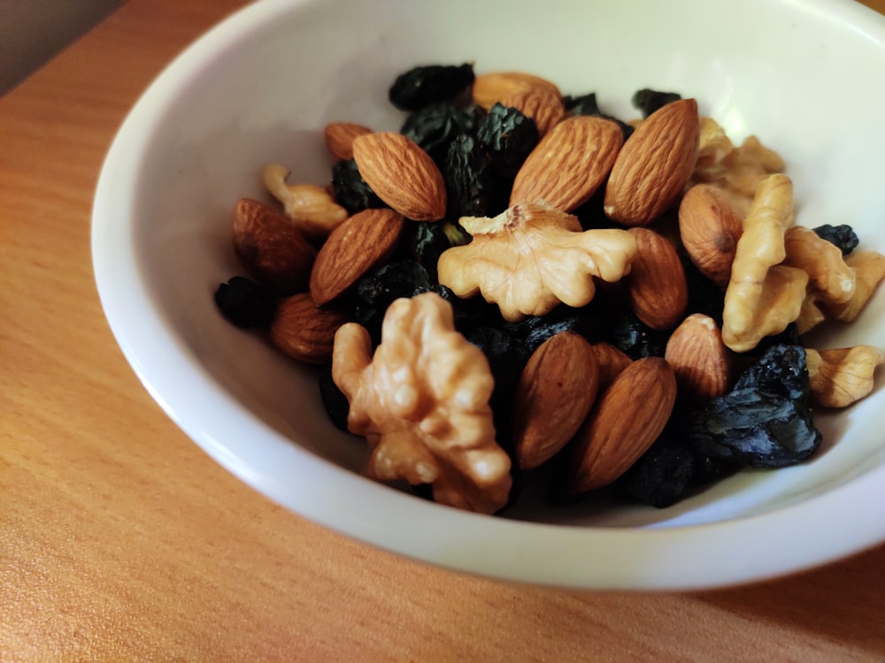 nueces marrones y negras en un cuenco de cerámica blanca