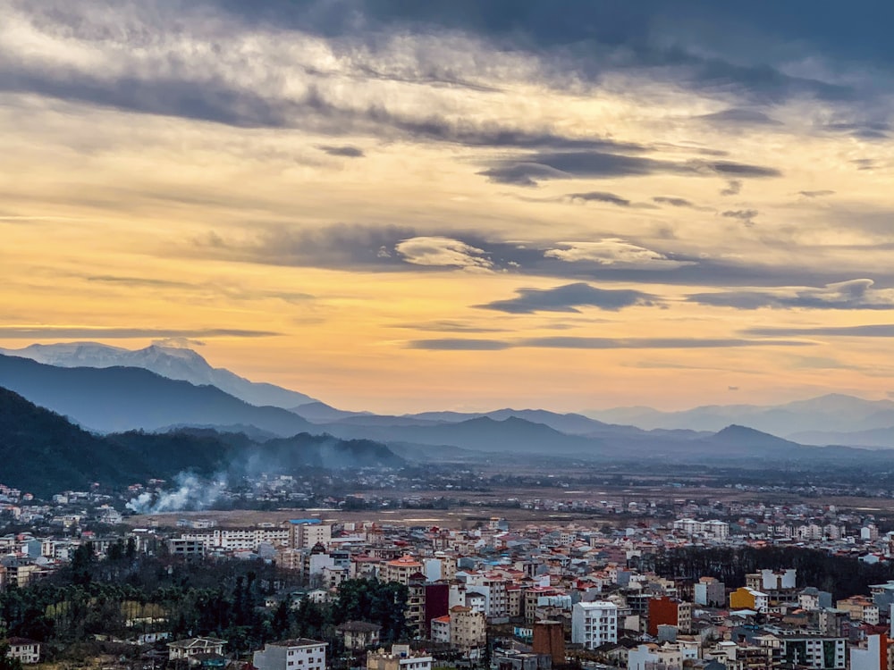 city with high rise buildings under orange and gray cloudy sky during sunset