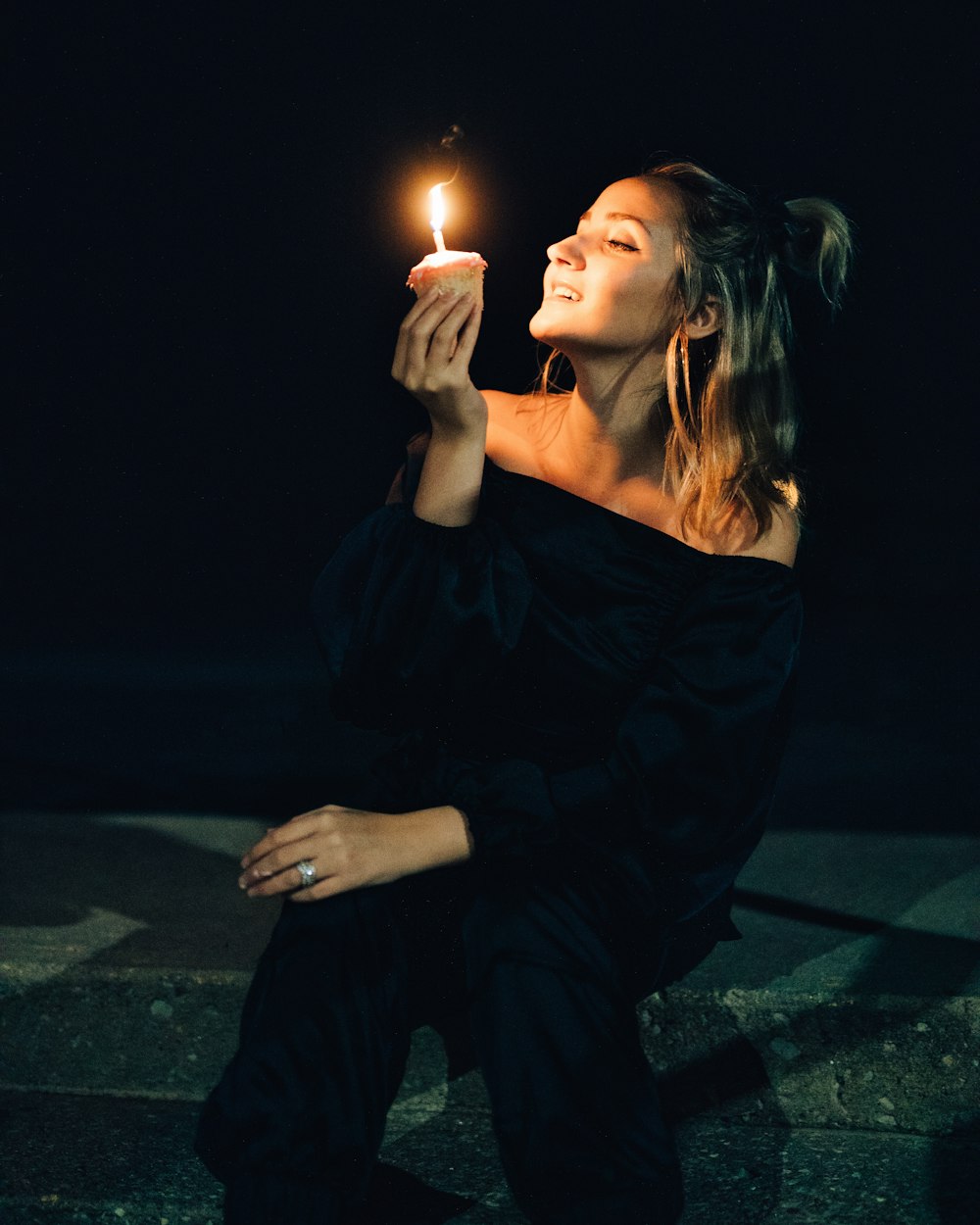 woman in black dress holding lighted candle