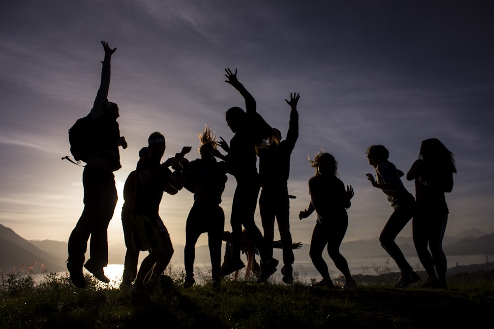 silhouette of people standing on green grass field during daytime