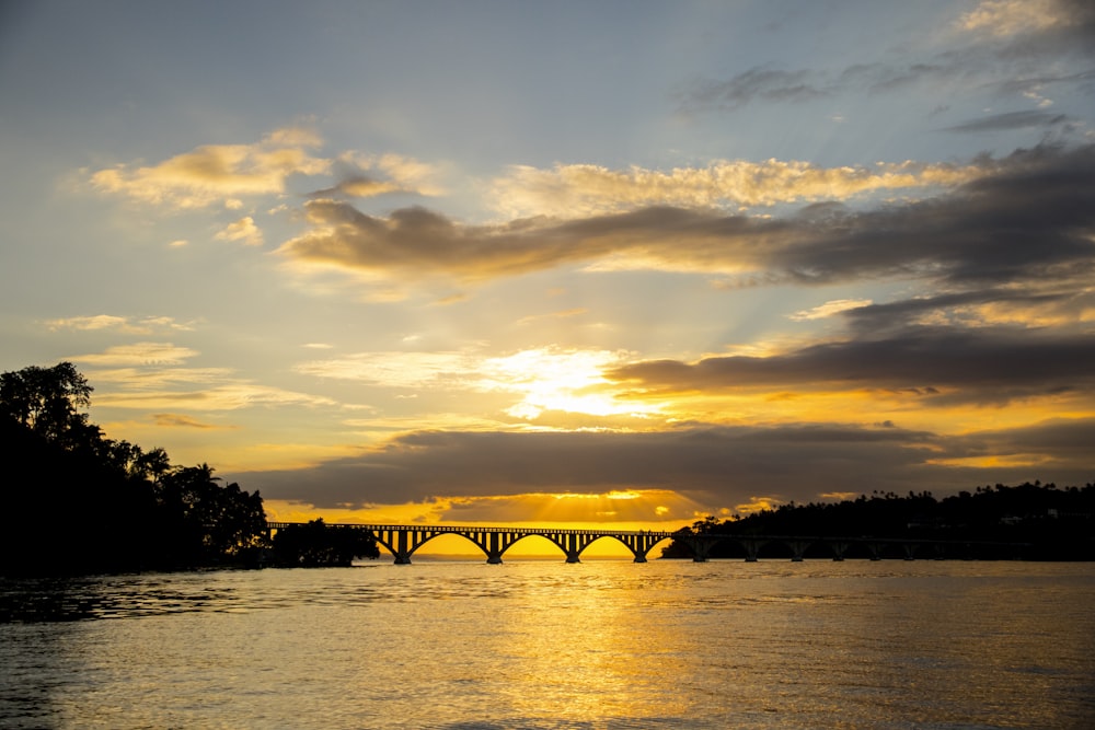 Silueta del puente sobre el cuerpo de agua durante la puesta del sol