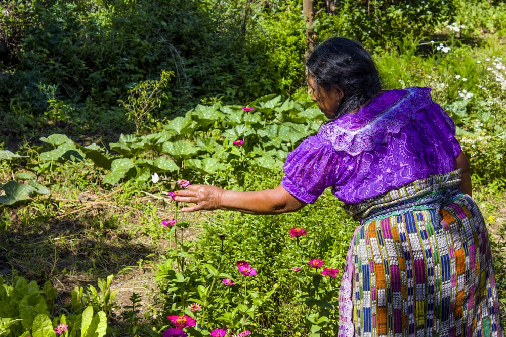 woman in purple shirt and green skirt standing on green grass field during daytime