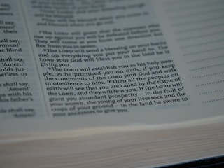 A close-up view of a printed page from a book with text in English, featuring prominent religious themes and mentioning 'The Lord', 'commandments', and 'prosperity'. The focus is on the center of the page, and text is clear and legible. The page edges are slightly blurred.