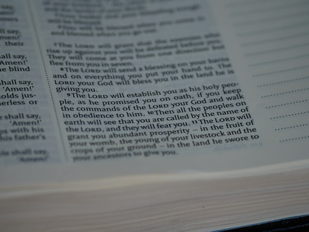 A close-up view of a printed page from a book with text in English, featuring prominent religious themes and mentioning 'The Lord', 'commandments', and 'prosperity'. The focus is on the center of the page, and text is clear and legible. The page edges are slightly blurred.