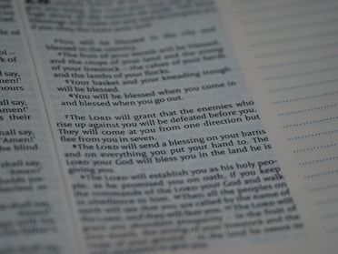 Text from a religious or spiritual book is visible on an open page. The words are printed in a formal font, and the page is filled with neatly organized columns of text. The focus is on a specific passage that appears to be discussing blessings and protection.