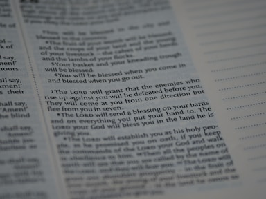 Text from a religious or spiritual book is visible on an open page. The words are printed in a formal font, and the page is filled with neatly organized columns of text. The focus is on a specific passage that appears to be discussing blessings and protection.