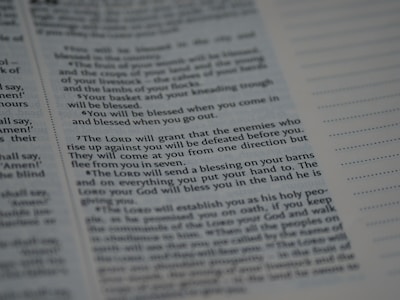 Text from a religious or spiritual book is visible on an open page. The words are printed in a formal font, and the page is filled with neatly organized columns of text. The focus is on a specific passage that appears to be discussing blessings and protection.