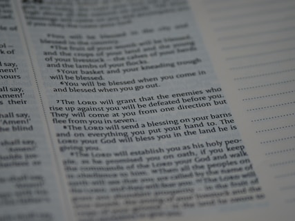 Text from a religious or spiritual book is visible on an open page. The words are printed in a formal font, and the page is filled with neatly organized columns of text. The focus is on a specific passage that appears to be discussing blessings and protection.