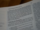 An open page of a book with text that includes a religious context, possibly from a Bible. The page is slightly tilted, and the focus is on the middle section of the page, making the text towards the edges blurry. The text appears to discuss themes related to divine blessings and instructions.