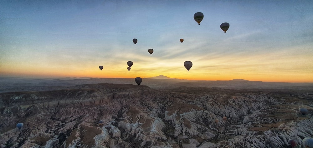 balões de ar quente voando sobre as montanhas durante o pôr do sol