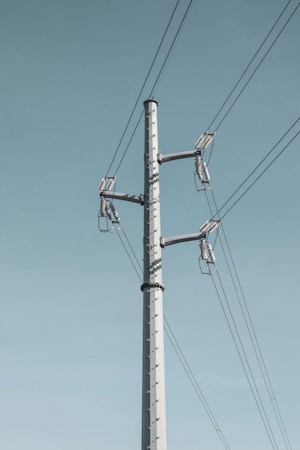 Close view of a distribution pole carrying multiple electrical wires and a transformer, the type of equipment that serves a few hundred nearby homes