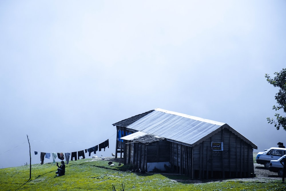 gray wooden house on green grass field under gray sky