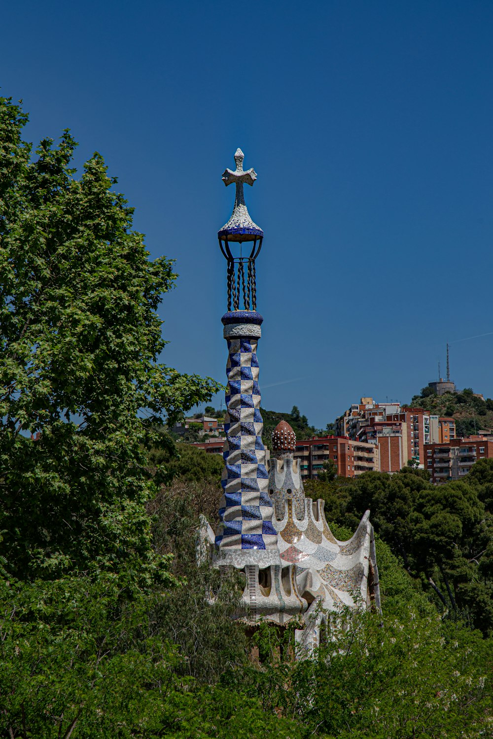 white and blue tower near green trees under blue sky during daytime