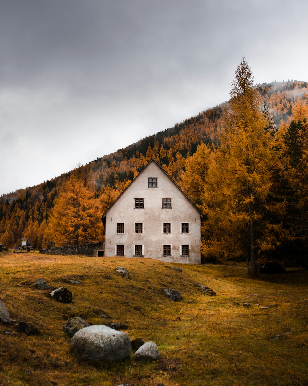 white and brown house on green grass field near trees under white clouds during daytime