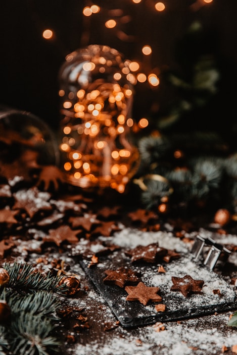 A festive holiday table setting featuring a plate of assorted spiced cookies with twinkling lights in the background.