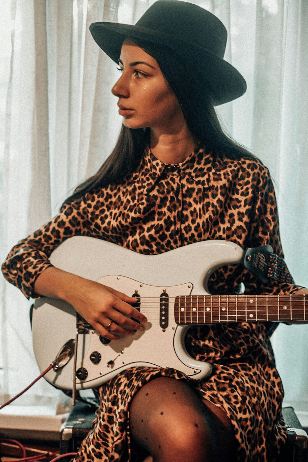 woman in black hat playing white electric guitar
