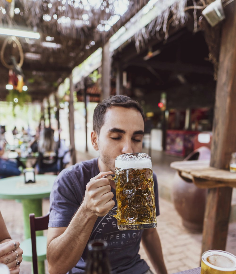 Mann im grauen Rundhals-T-Shirt Bier trinken