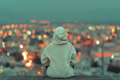 person in white hoodie sitting on gray concrete floor during daytime
