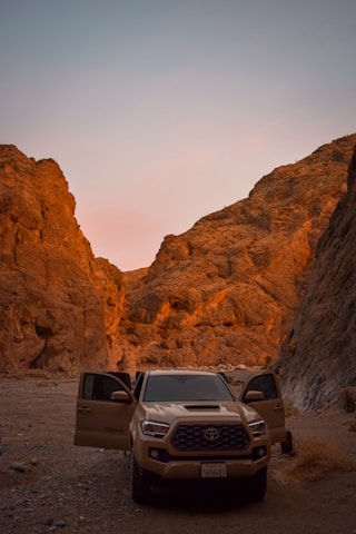A sturdy tow truck parked on a desert road at sunset with warm earthy tones in the background.