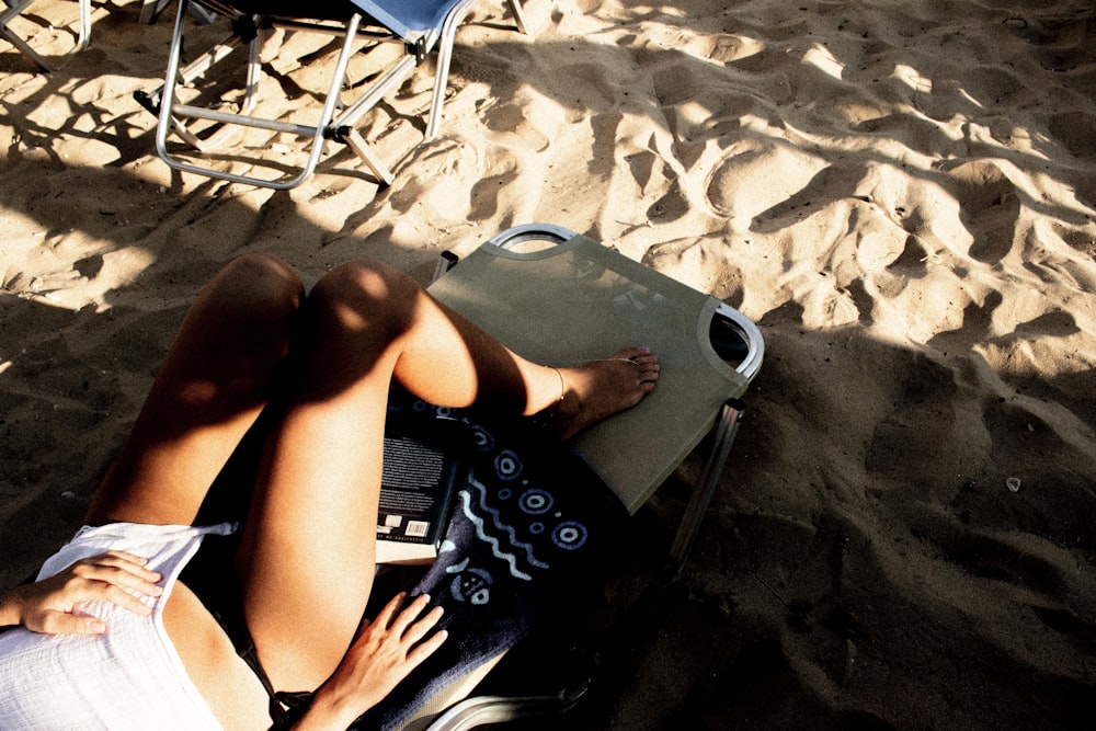 woman in black and white bikini lying on white beach lounge chair
