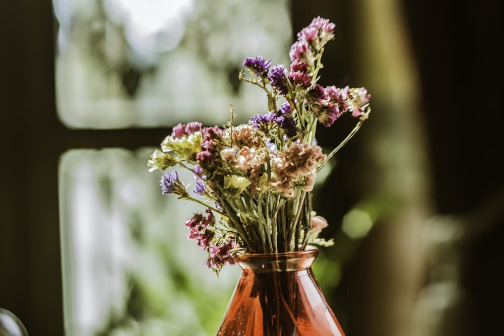 pink and yellow flowers in red glass vase