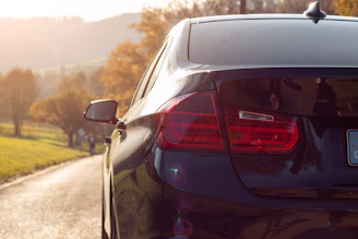 Wide shot of a car on a scenic road with mountains in the background during golden hour