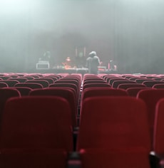 people sitting on red chairs watching a band performing on stage